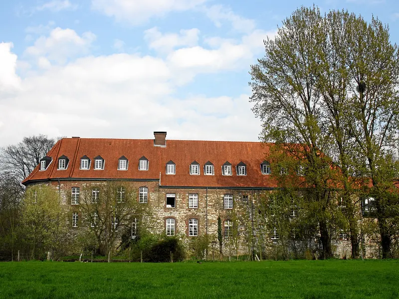 Burg Angermund mit roten Dächern hinter einer grünen Wiese in Düsseldorf-Angermund
