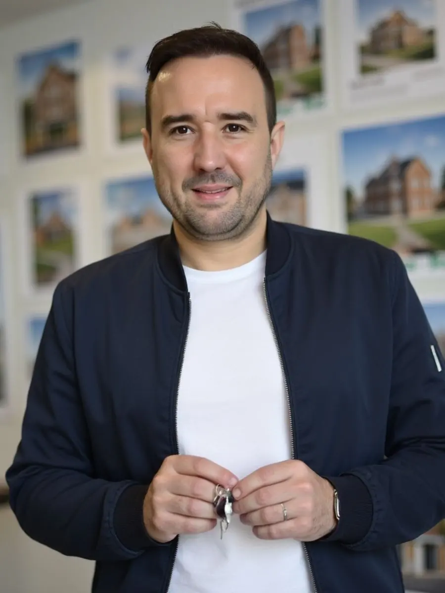 Christian Gottschling, Immobilienmakler für Ratingen, hält einen Hausschlüssel vor Immobilienfotos