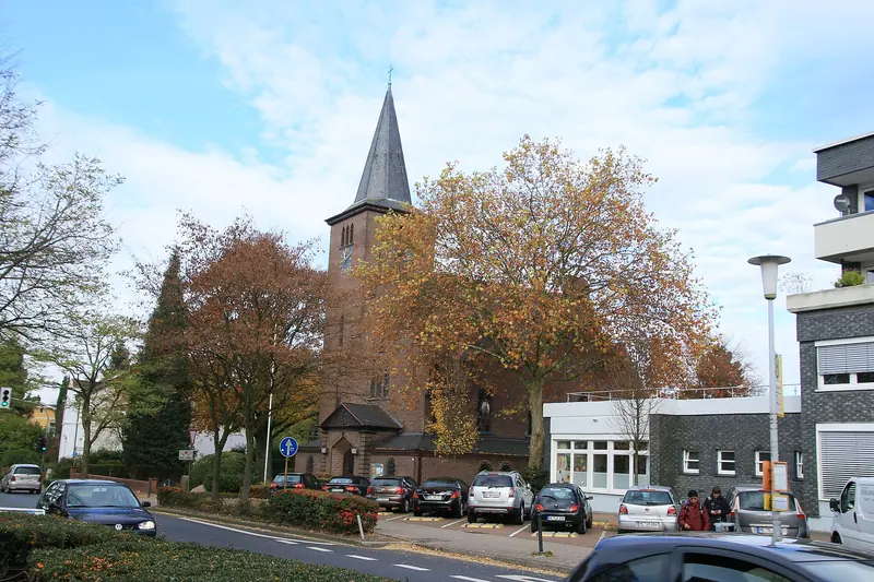 Evangelische Adolf-Clarenbach-Kirche zwischen bunten Herbstbäumen im Ortskern von Ratingen-Hösel