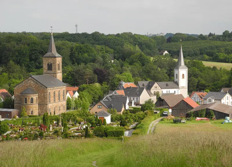 Blick über Wiesen auf den Ortsteil Düssel mit zwei Kirchtürmen in Wülfrath